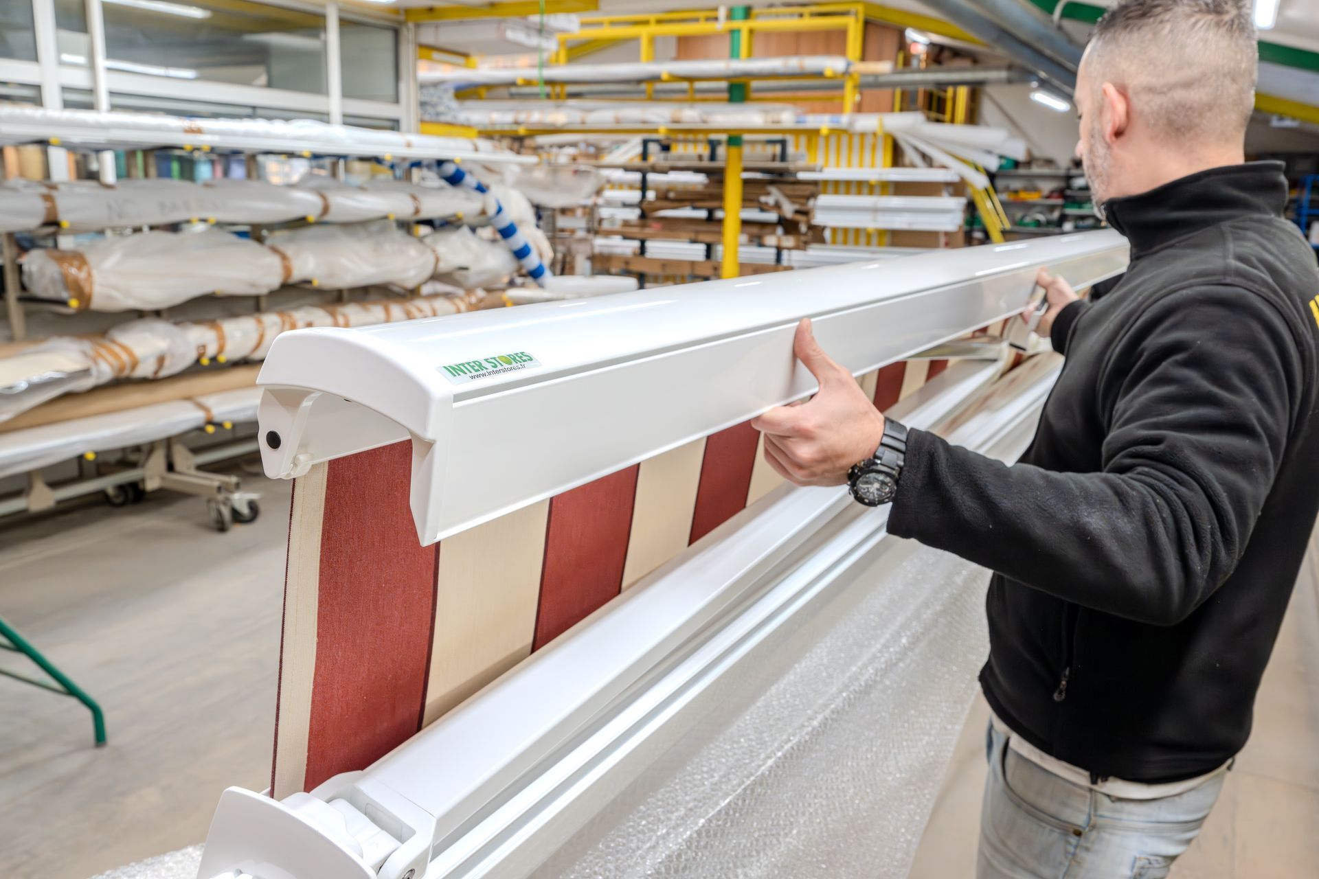 Homme dans un atelier qui contrôle un store banne.