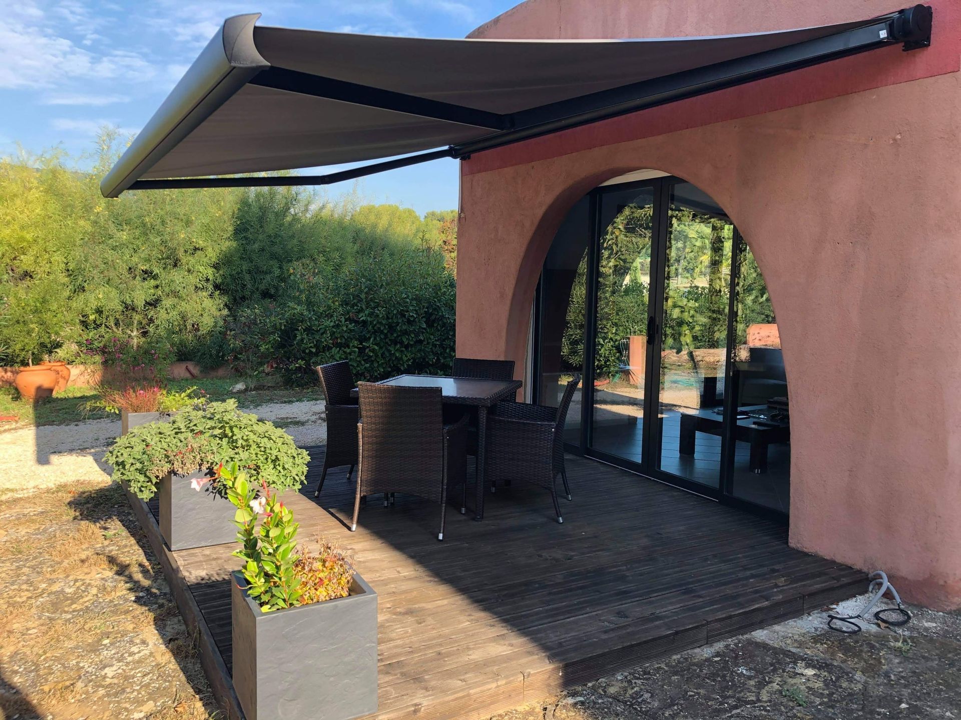 Maison avec façade rouge et un store banne.
