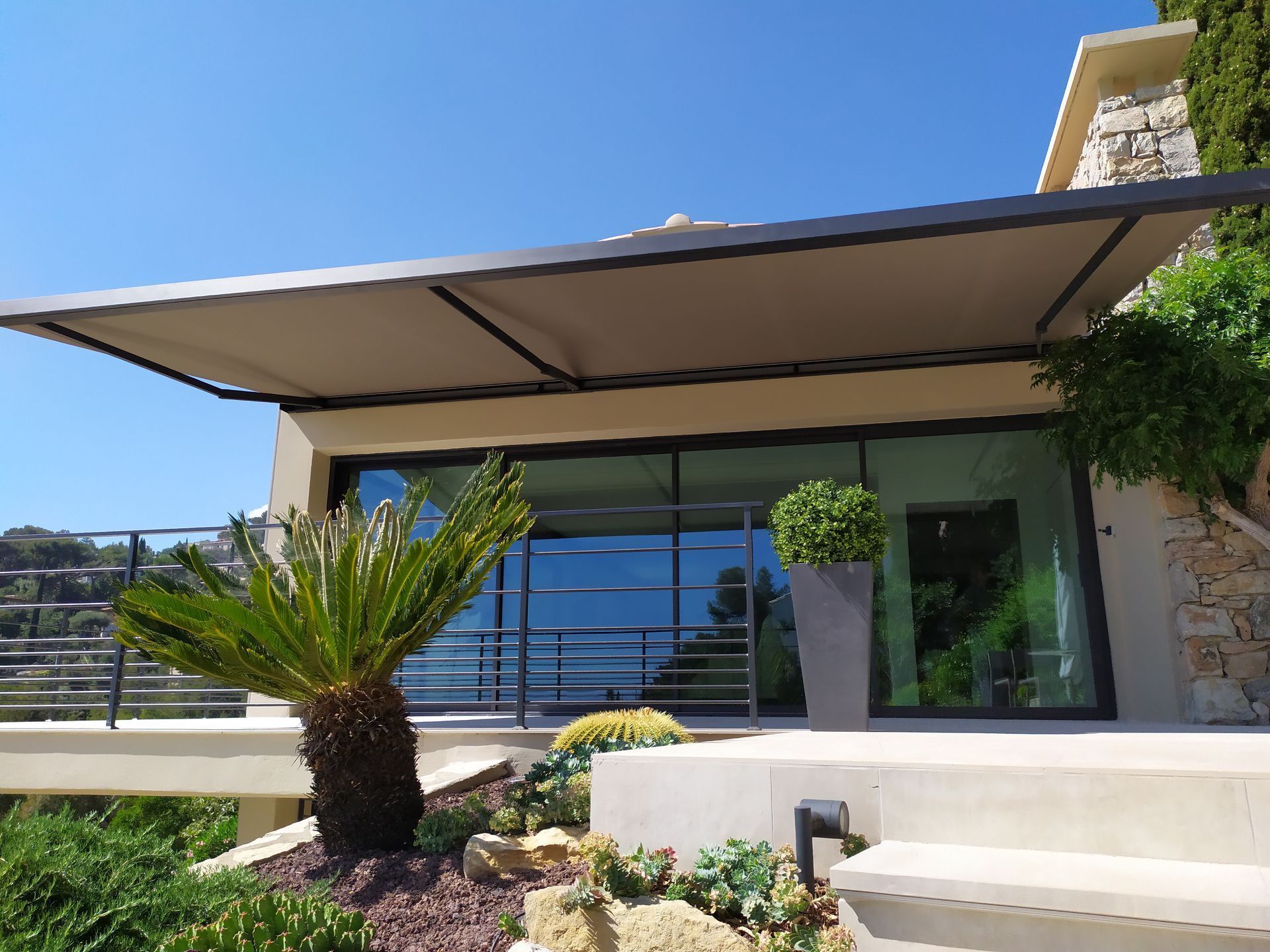 Belle maison avec une grande baie vitrée et un store banne.