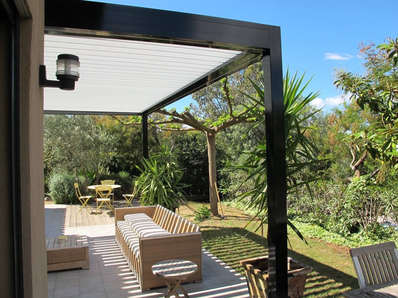 Pergola bioclimatique qui protège une terrasse en bois.