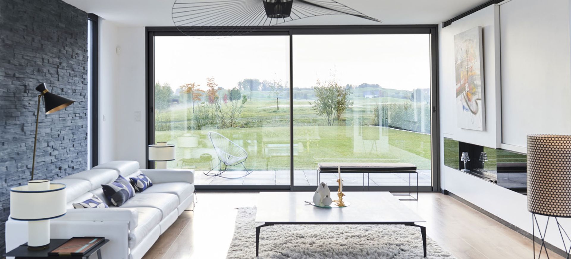 Salon avec une grande baie vitrée donnant sur le jardin d'une maison.