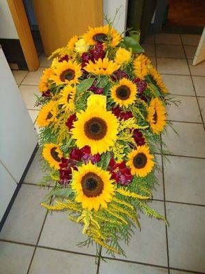 Ein Strauss Sonnenblumen steht auf einem gefliesten Boden. Foto von der Schöni Blumen und Gartenbau GmbH