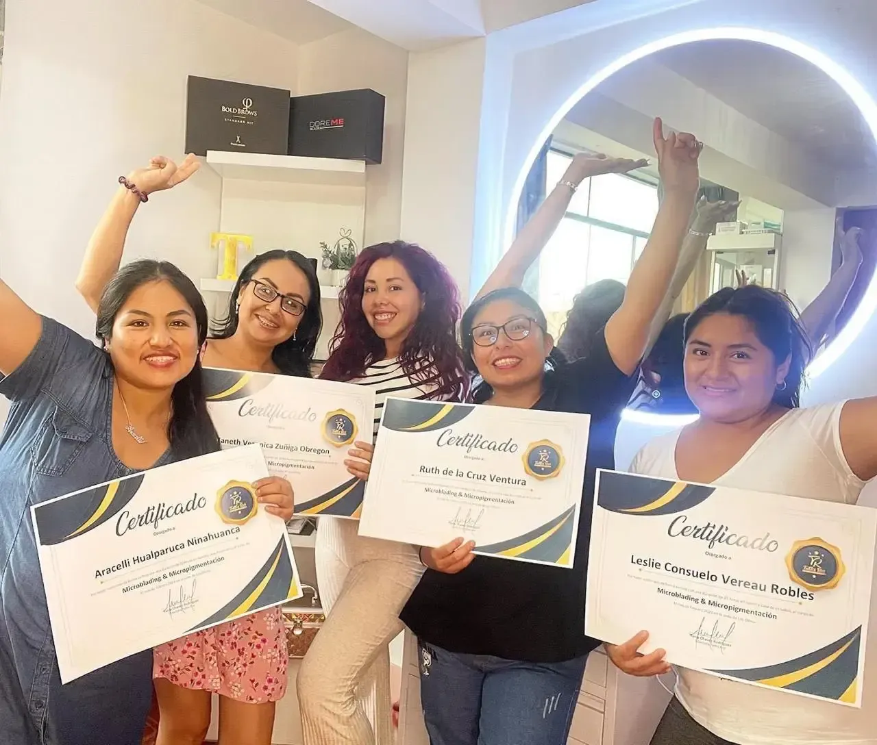Cinco personas sonrientes sostienen certificados en un salón de belleza