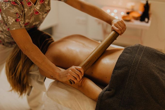 En un spa, un masajista utiliza una herramienta de madera con rodillo para masajear la espalda de un cliente.