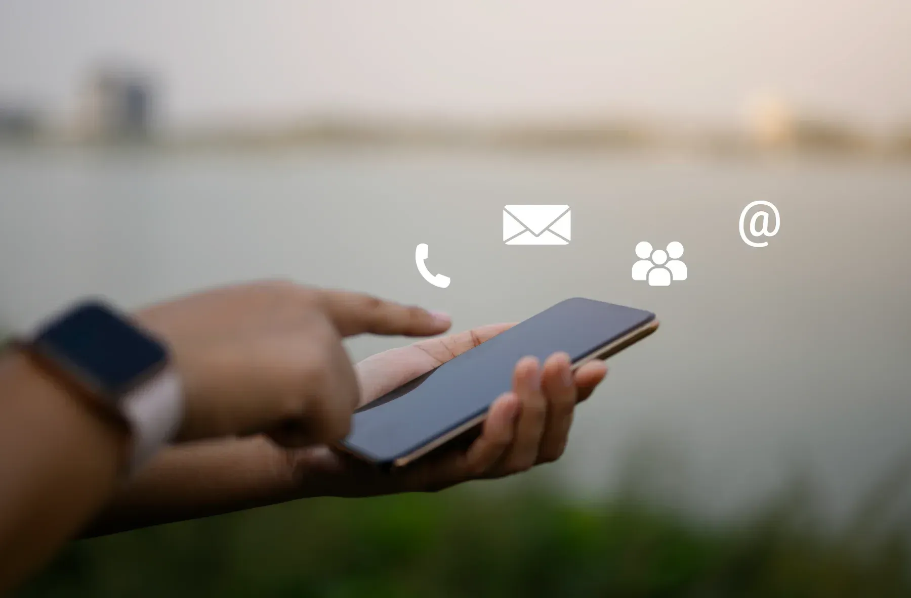 Persona que usa un teléfono inteligente con íconos de contacto: teléfono, correo electrónico, grupo y símbolo arroba.