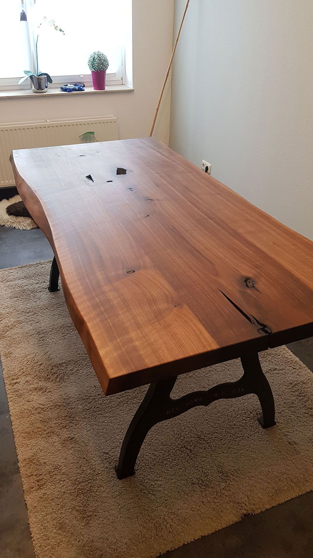 Ein Holztisch steht auf einem Teppich in einem Raum neben einem Fenster.