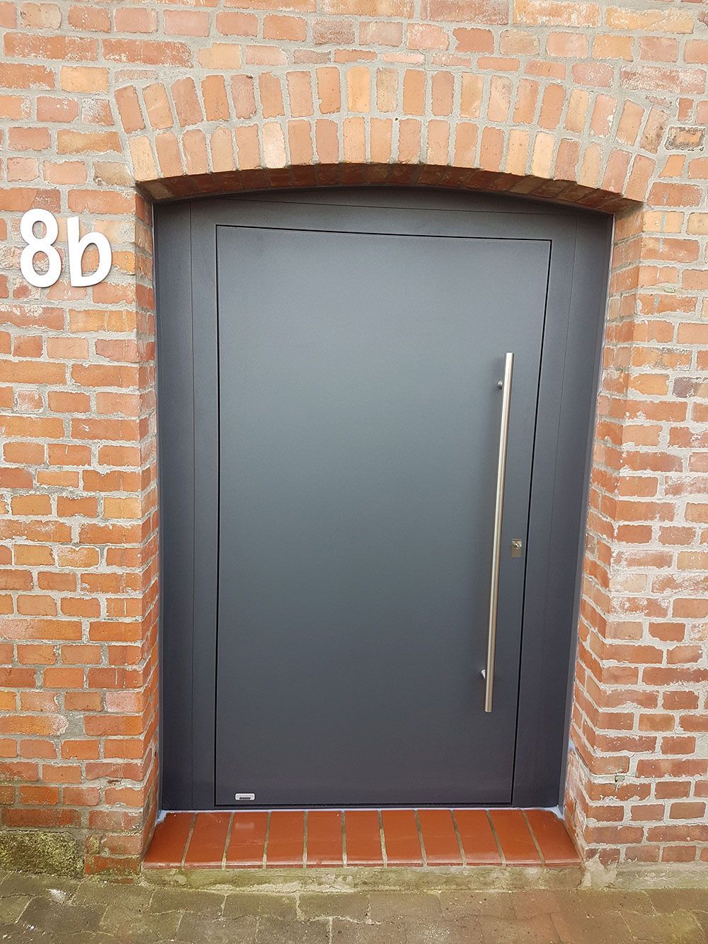 Ein Backsteingebäude mit einer schwarzen Tür und der Nummer 8b darauf