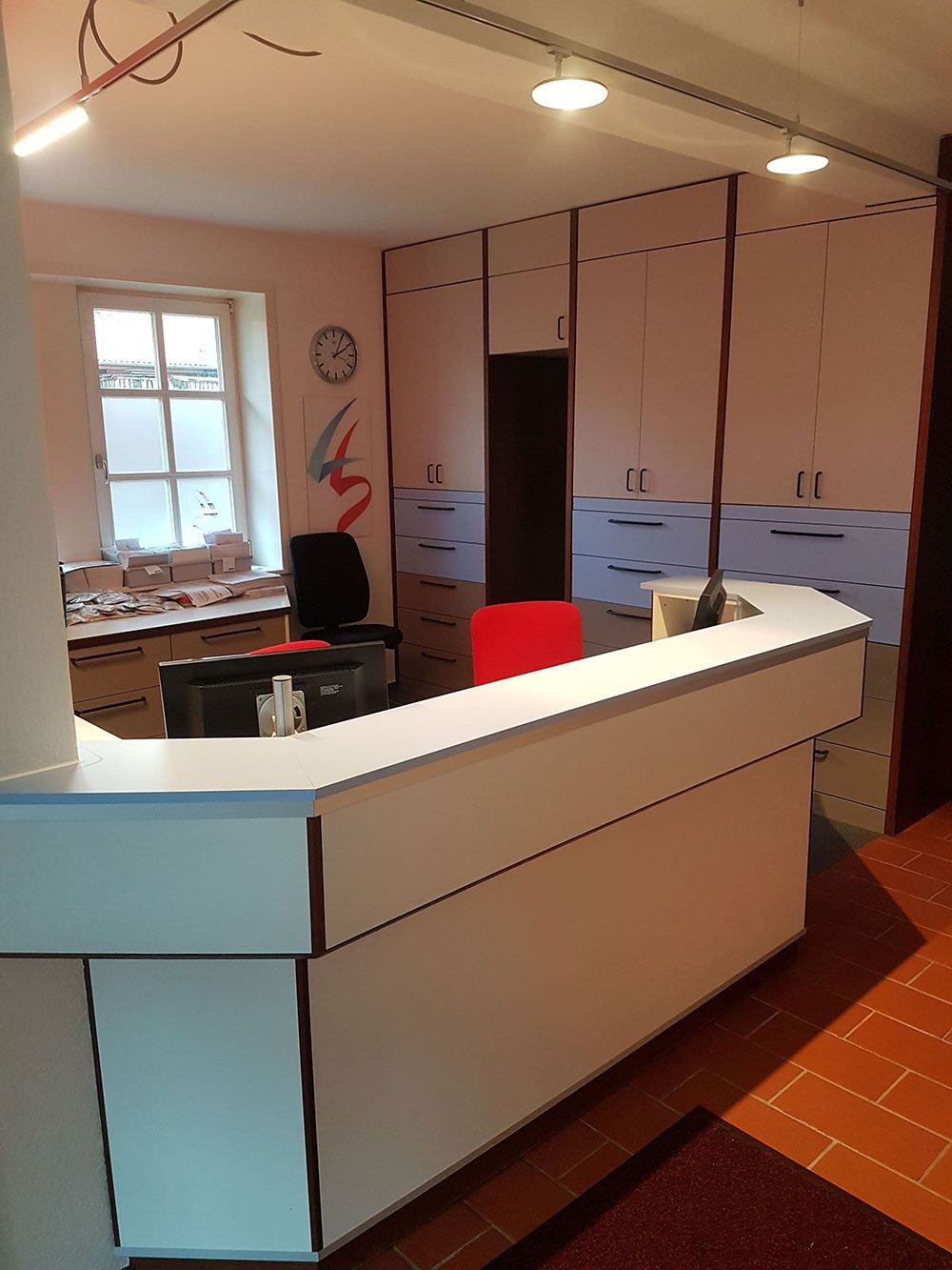 Ein Empfangsbereich mit einem weißen Tresen und einem roten Stuhl