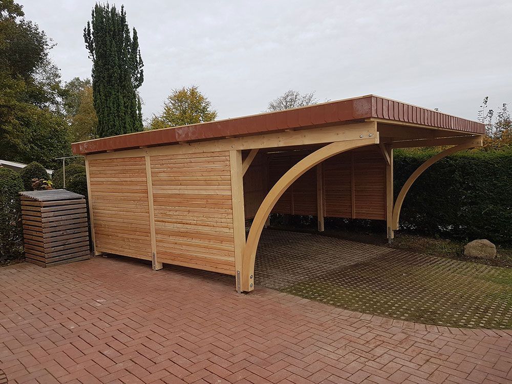 Auf einer gepflasterten Auffahrt steht ein Carport aus Holz.