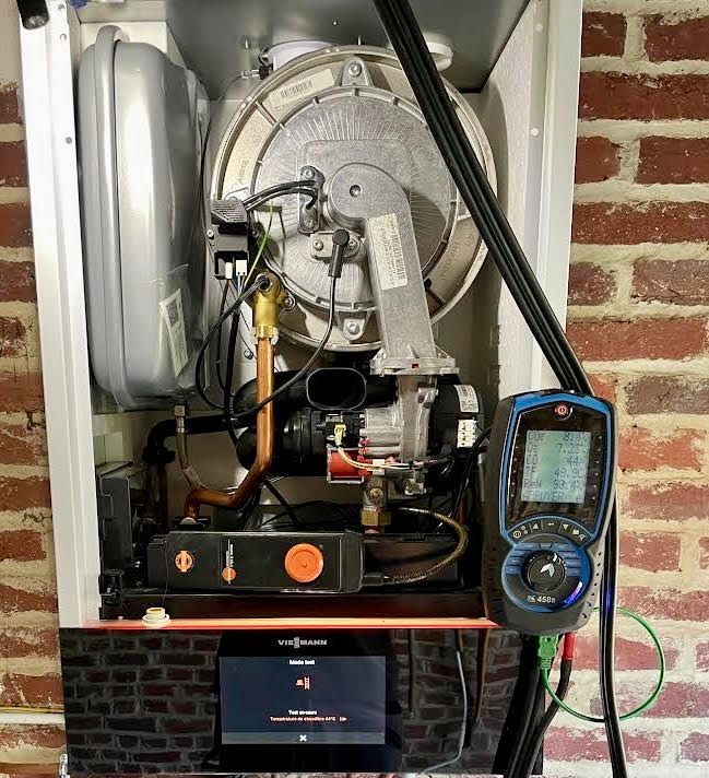 Intérieur d’une chaudière avec composants visibles, dont ventilateur, brûleur et chambre de combustion.