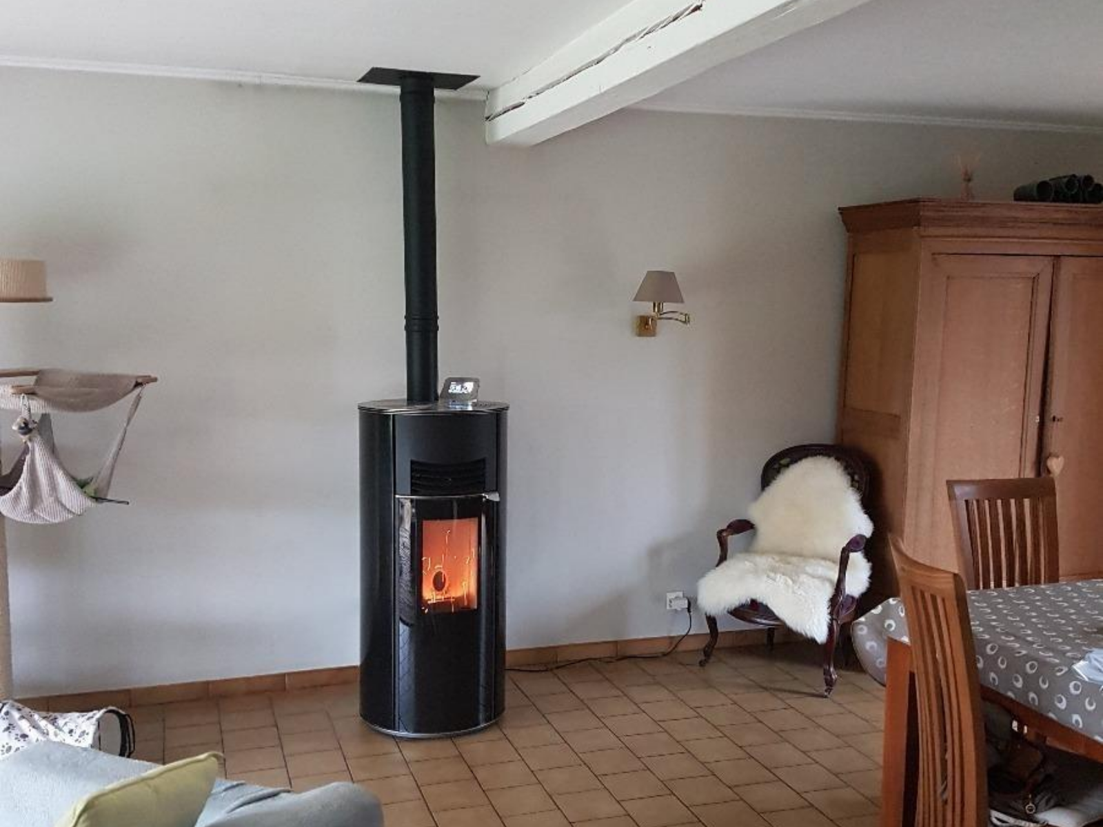 Poêle à granulés noir en fonctionnement dans un salon, avec mobilier en bois autour.