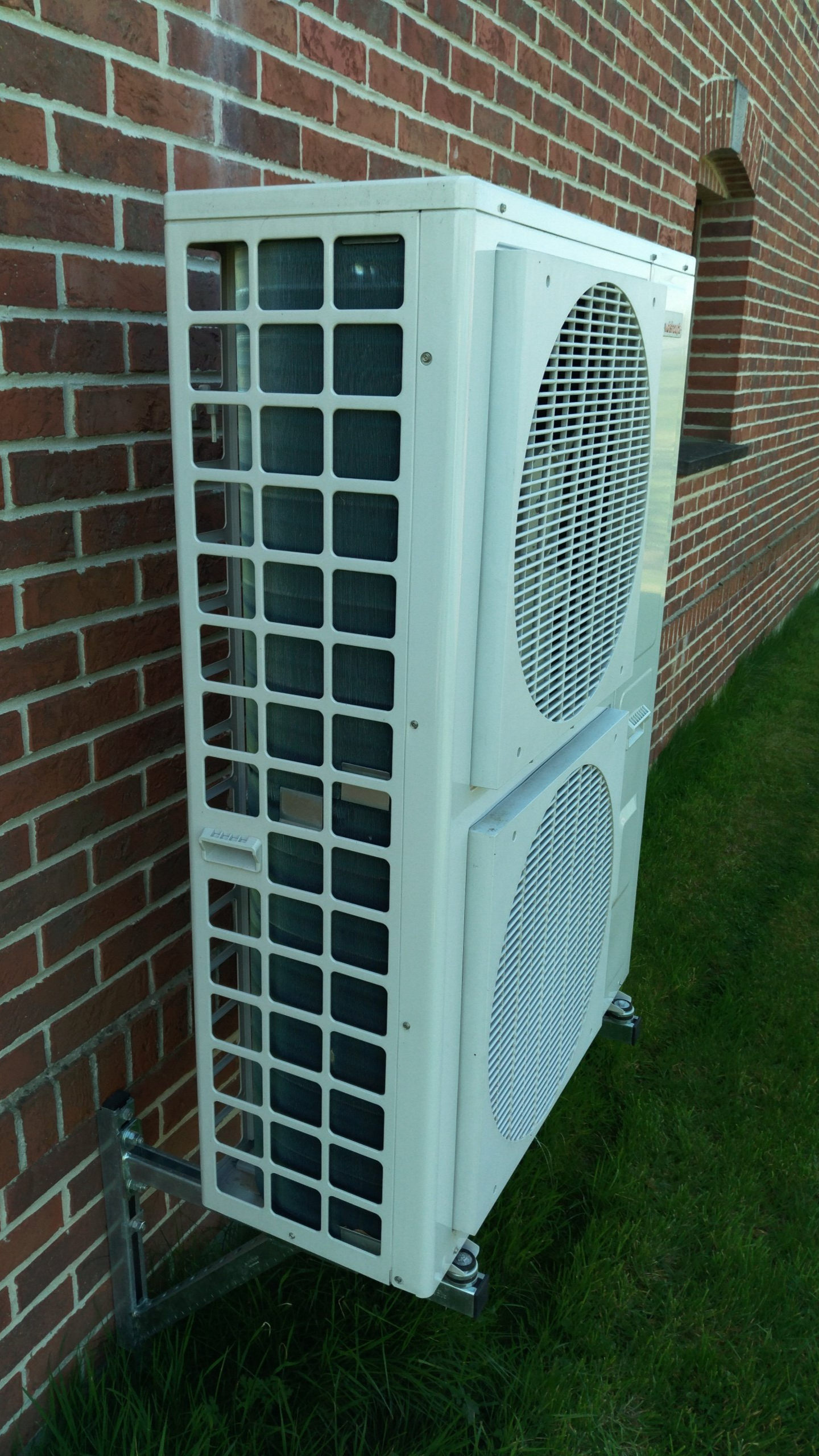 Pompe à chaleur extérieure fixée sur un mur en briques.