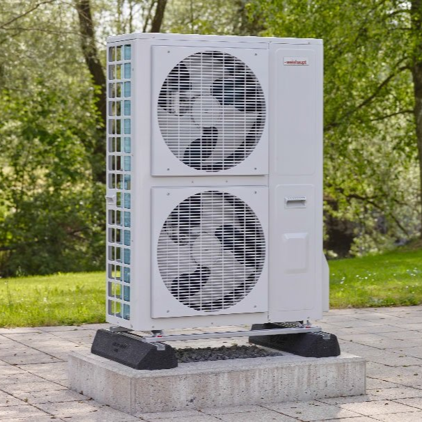 Pompe à chaleur extérieure avec deux ventilateurs, installée sur une dalle en béton.