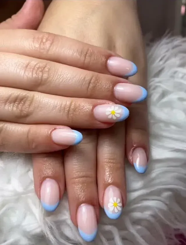 Manos con uñas de color rosa pastel y azul degradado, algunas con pequeños diseños de margaritas.