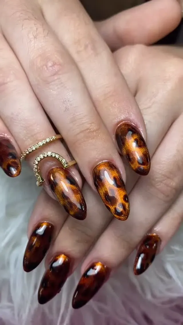 Manos con largas uñas acrílicas con estampado de carey