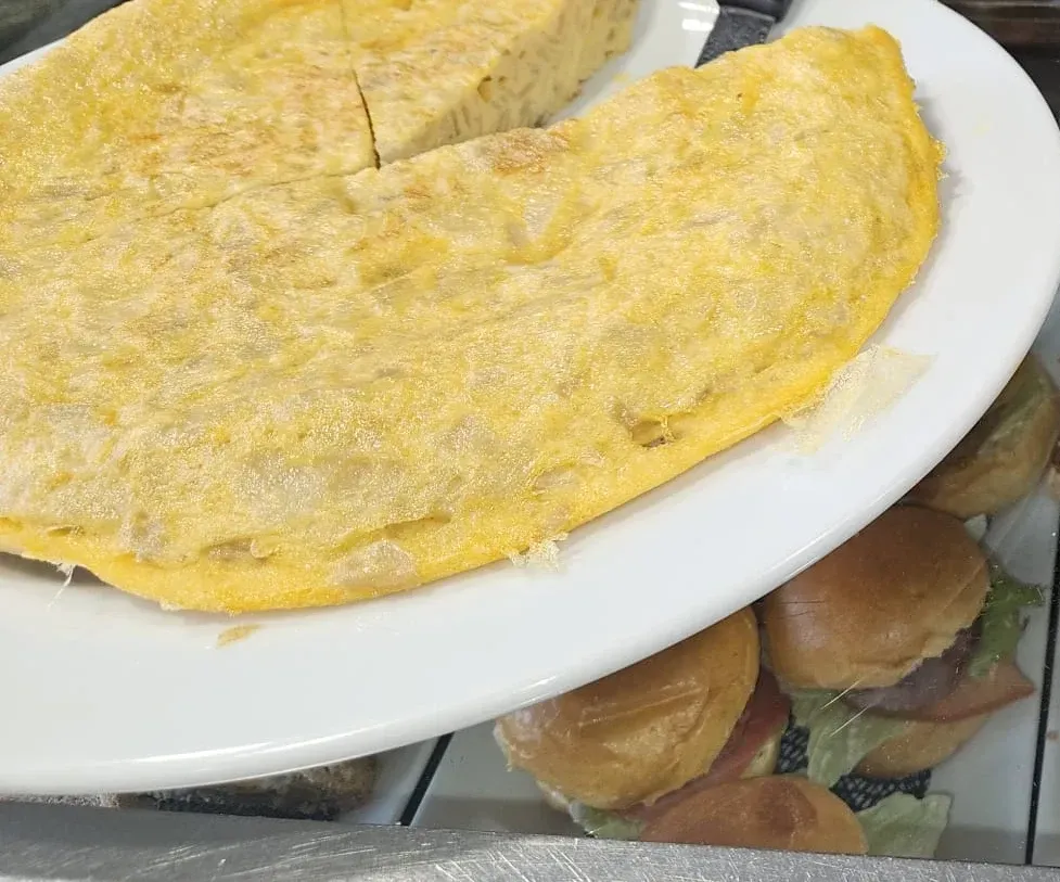 Un plato blanco cubierto con una tortilla y hamburguesas.