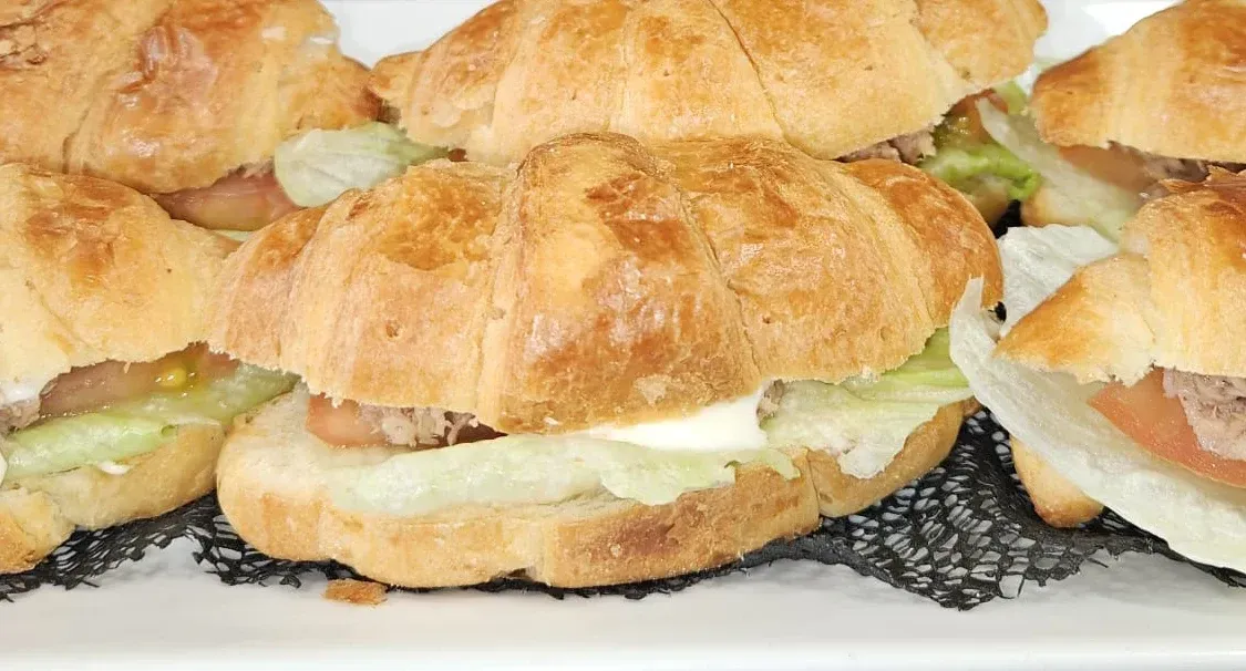 Un primer plano de un plato de sándwiches con croissants sobre una mesa.