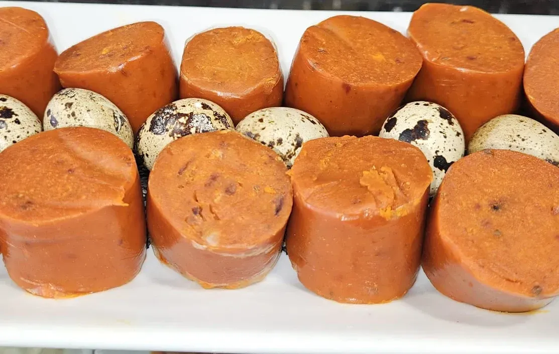 Un plato blanco cubierto con salchichas y huevos de codorniz.