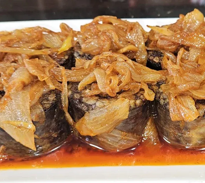 Un primer plano de un plato de comida con cebollas encima.