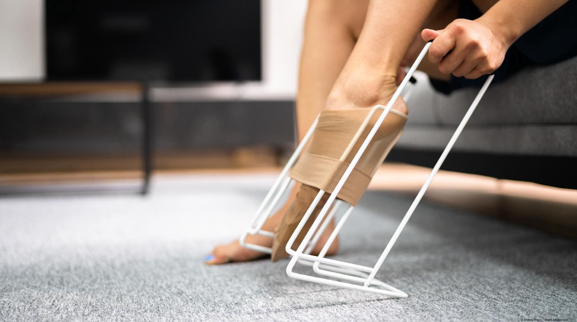Person sitzt auf dem Boden und nutzt eine Anziehhilfe