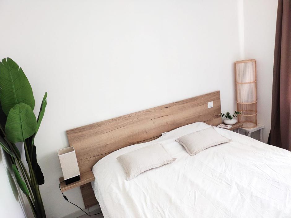 Lit avec des draps blancs et une tête de lit en bois