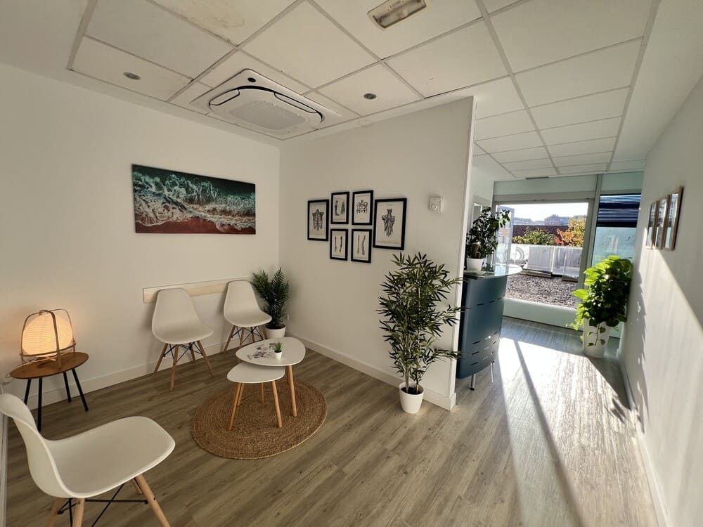 Una sala de espera con sillas, mesas y un cuadro en la pared.