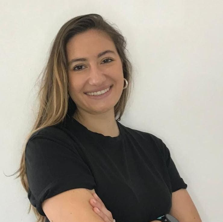 Una mujer con una camisa negra sonríe con los brazos cruzados.