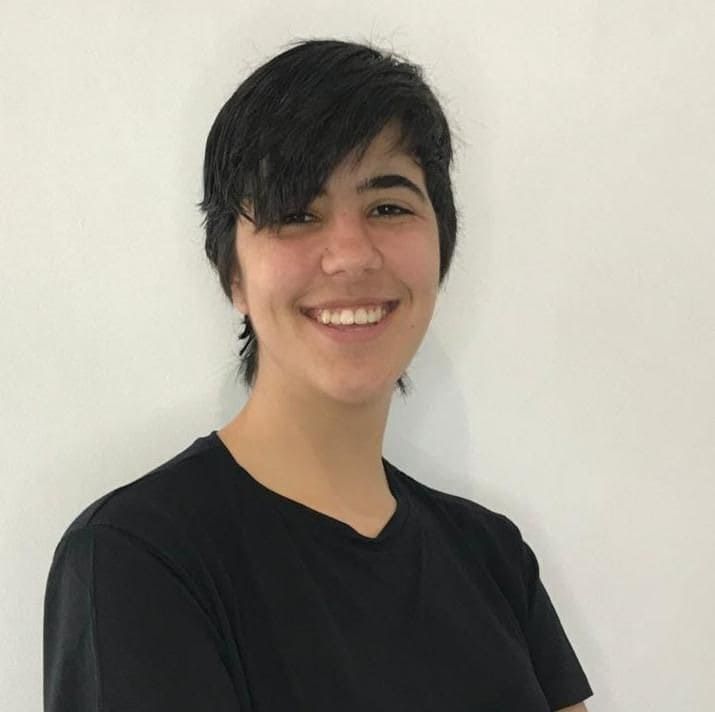 Una mujer joven que lleva una camisa negra sonríe a la cámara.