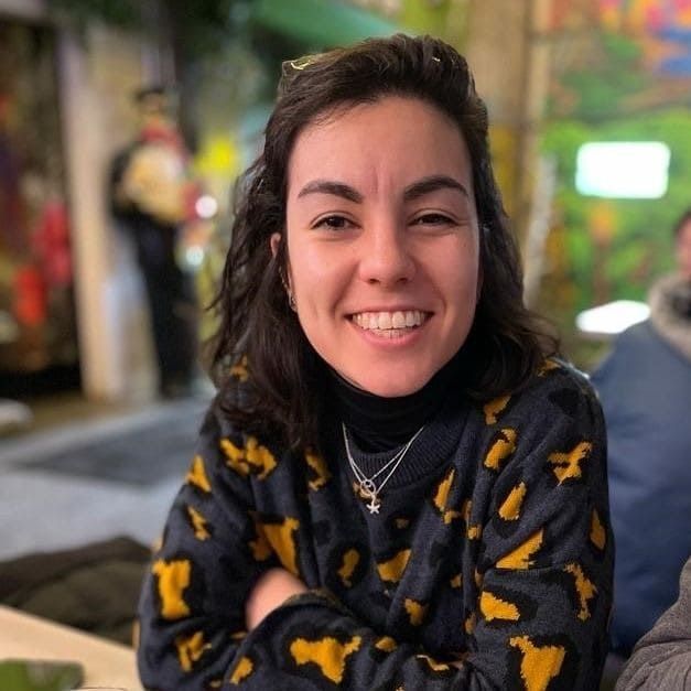 Una mujer que lleva un suéter con estampado de leopardo sonríe a la cámara.