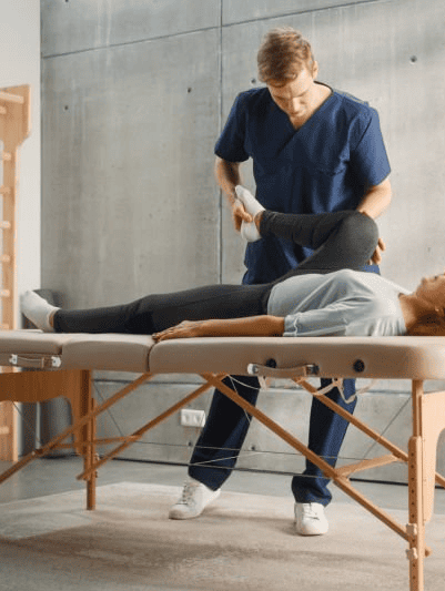 Un hombre está estirando la pierna de una mujer sobre una mesa.