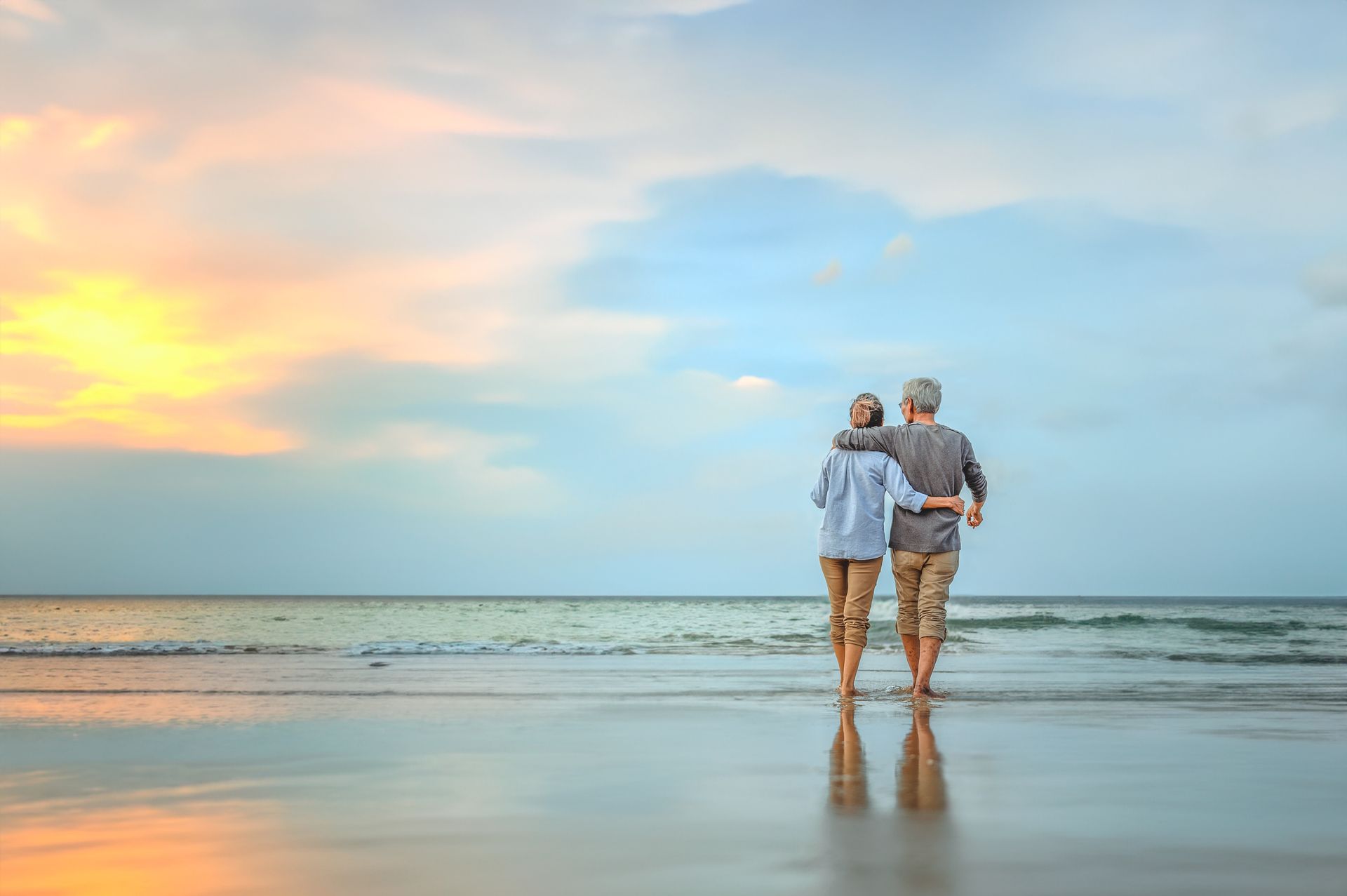 Un couple de seniors se promène sur la plage au coucher du soleil