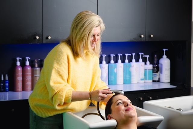  vrouw die het haar van een andere vrouw wast in een kapsalon