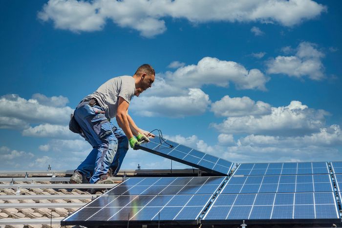 Deux hommes installent des panneaux solaires sur un toit