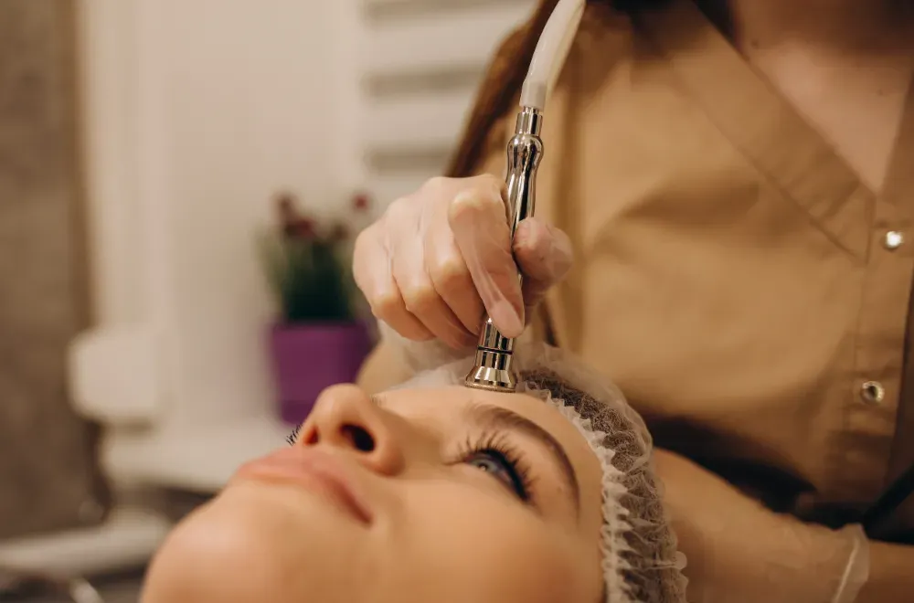 Una persona recibe un tratamiento facial de microdermoabrasión con un dispositivo manual en la frente en un spa.
