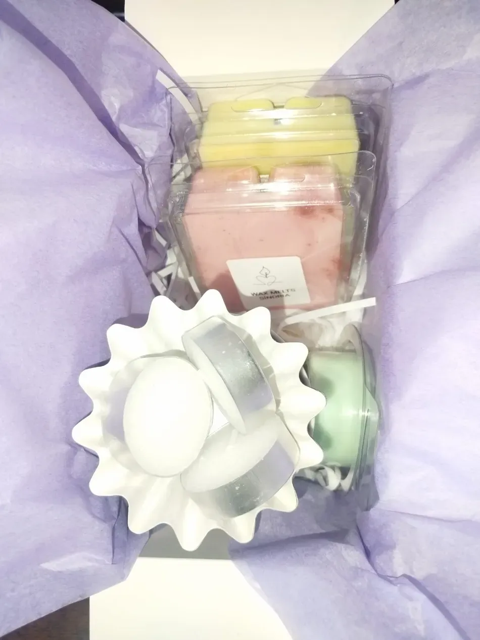 Bolsa de regalo morada que contiene pequeños artículos variados, incluyendo un objeto blanco con forma de flor y recipientes de colores pastel.