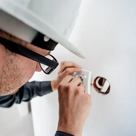 Un hombre que lleva casco y gafas está instalando un interruptor de luz.