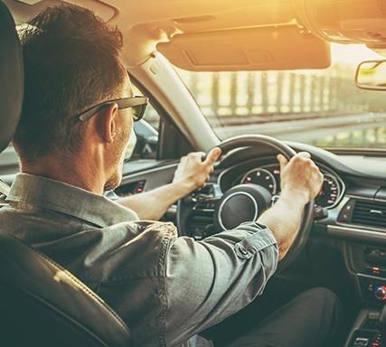Familia de cuatro personas sonriéndose unos a otros, sentados en el suelo frente a un sofá, en el interior.