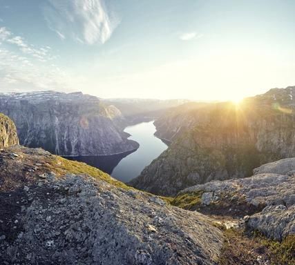 Familia de cuatro personas sonriéndose unos a otros, sentados en el suelo frente a un sofá, en el interior.