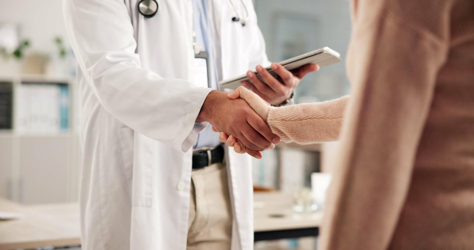 Familia de cuatro personas sonriéndose unos a otros, sentados en el suelo frente a un sofá, en el interior.
