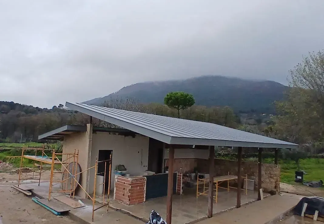 En el campo se está construyendo una pequeña casa con techo de metal.