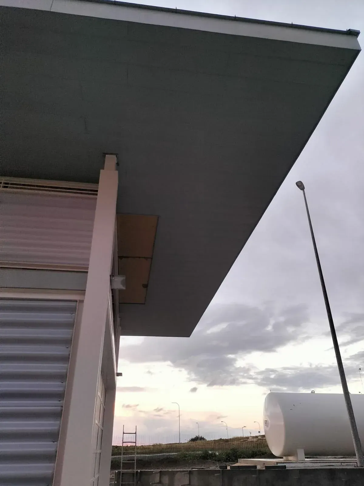 El techo de un edificio con un gran tanque blanco delante.