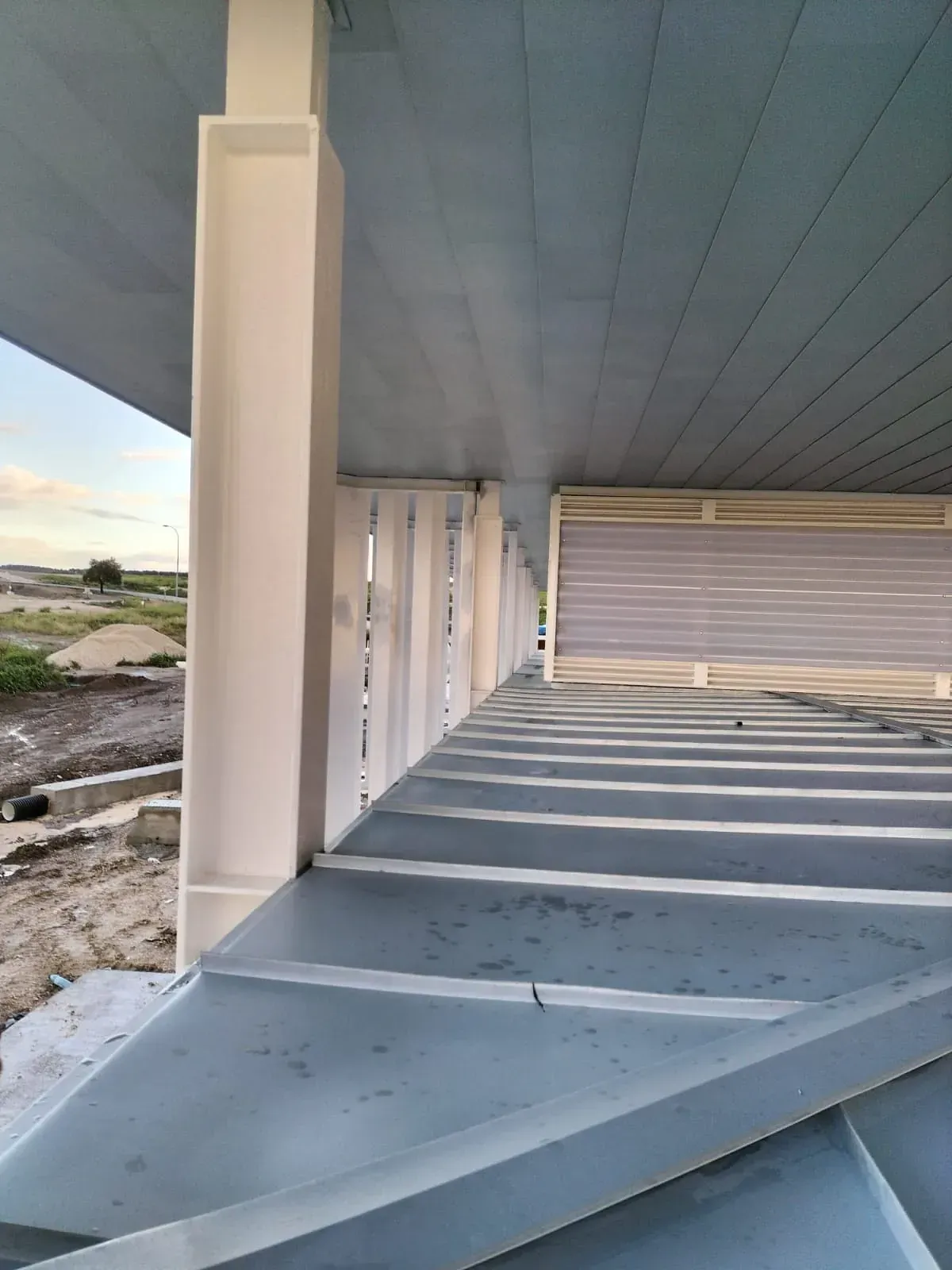 Un edificio en construcción con techo azul y pilares blancos.