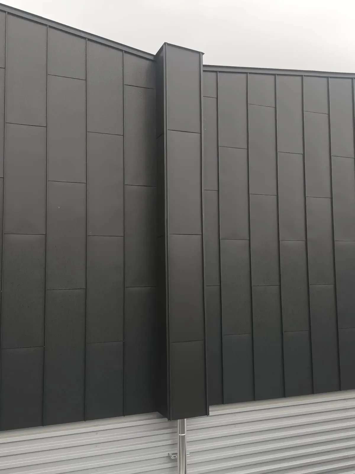 Un edificio negro con una valla blanca delante.