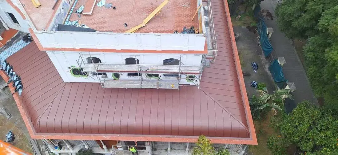Una vista aérea de un edificio en construcción con un techo de tejas rojas.