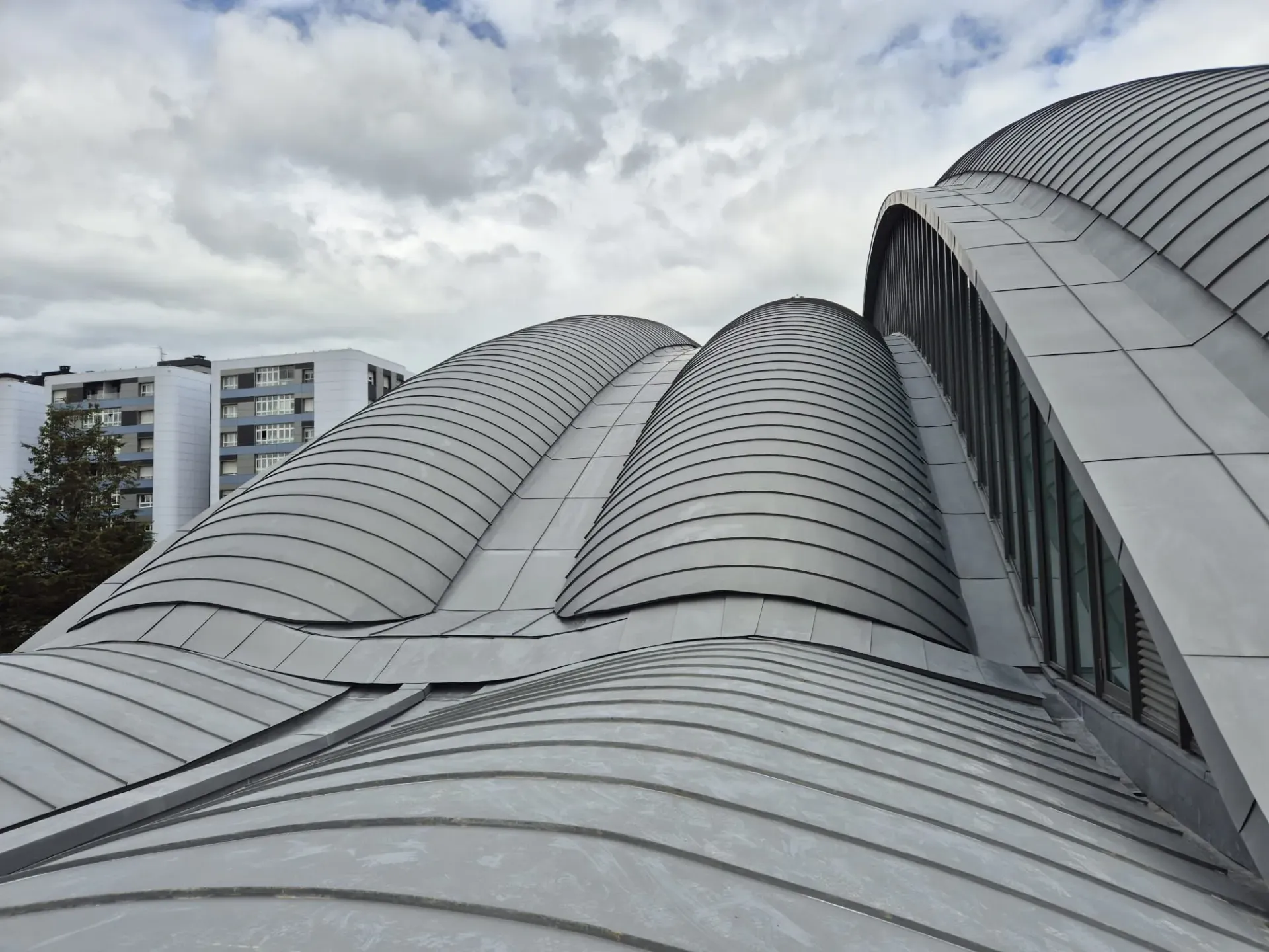 Mirando hacia el techo de un edificio con un cielo nublado en el fondo.