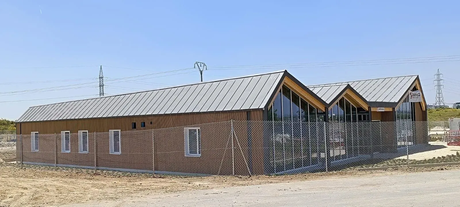 Se está construyendo un gran edificio de ladrillo con techo de metal.