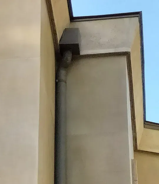 Un primer plano de una canaleta en el costado de un edificio.