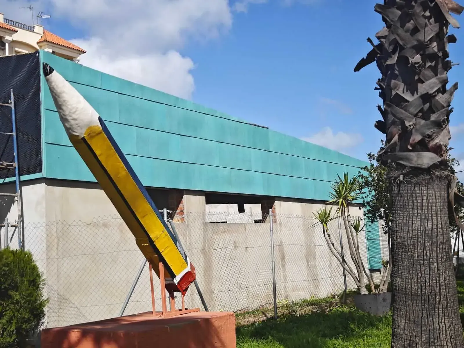 Una estatua de un lápiz gigante frente a un edificio.