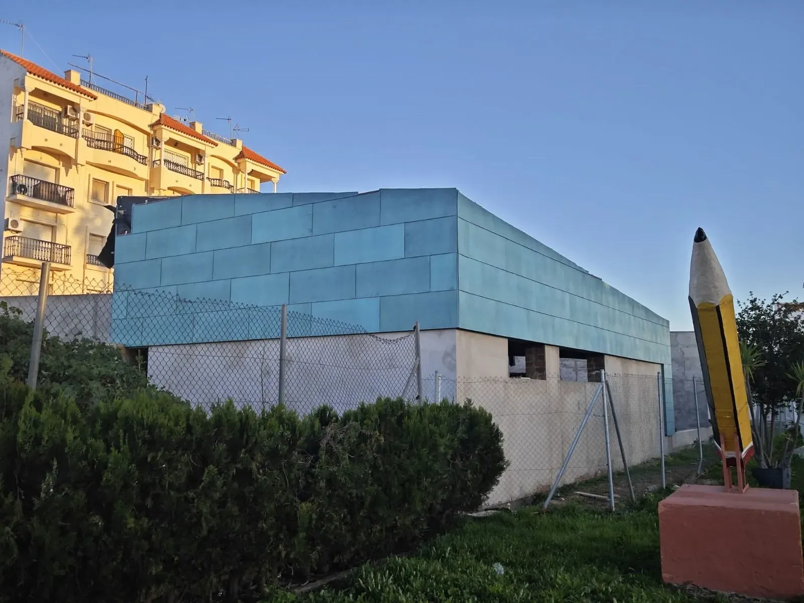 Una gran estatua de lápiz está frente a un edificio.