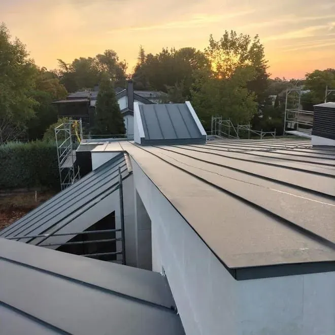 Un tejado de un edificio con una puesta de sol al fondo